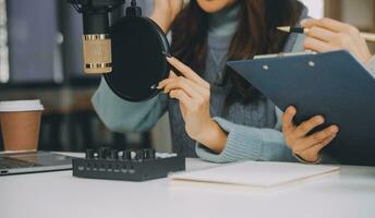 Woman recording a podcast on her laptop computer with headphones and a microscope. Female podcaster making audio podcast from her home studio. photo