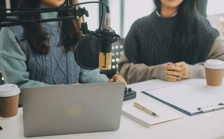 Woman recording a podcast on her laptop computer with headphones and a microscope. Female podcaster making audio podcast from her home studio. photo