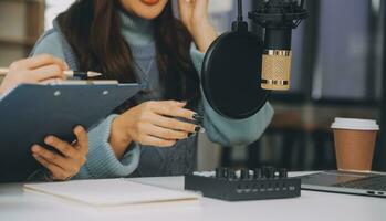 Woman recording a podcast on her laptop computer with headphones and a microscope. Female podcaster making audio podcast from her home studio. photo