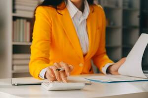 Close up woman work on project sit at desk use laptop and calculator, look at pc screen with diagrams, calculates bills, check financial documents, leads accounting of company, plan investment concept photo