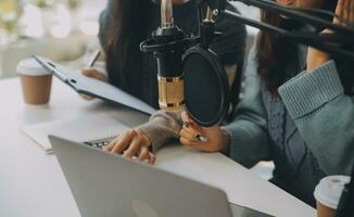 Woman recording a podcast on her laptop computer with headphones and a microscope. Female podcaster making audio podcast from her home studio. photo