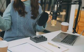 mujer grabando un podcast en su computadora portátil con auriculares y un microscopio. podcaster femenina haciendo podcast de audio desde su estudio en casa. foto