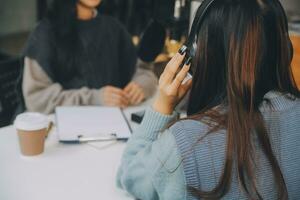 Woman recording a podcast on her laptop computer with headphones and a microscope. Female podcaster making audio podcast from her home studio. photo