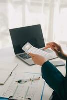 Businessman using a calculator to calculate numbers on a company's financial documents, he is analyzing historical financial data to plan how to grow the company. Financial concept. photo