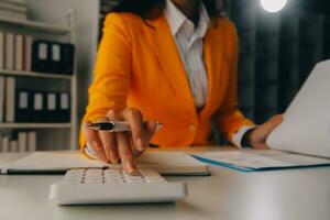 Close up woman work on project sit at desk use laptop and calculator, look at pc screen with diagrams, calculates bills, check financial documents, leads accounting of company, plan investment concept photo