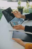 Charming Young asian businesswoman sitting on laptop computer in the office, making report calculating balance Internal Revenue Service checking document. photo