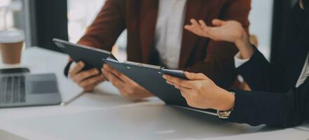 Financial analysts analyze business financial reports on a digital tablet planning investment project during a discussion at a meeting of corporate showing the results of their successful teamwork. photo