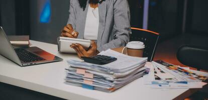 Woman sitting at her desk in home office working late at night using laptop computer female web designer working overtime remotely from home photo