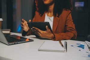 Woman sitting at her desk in home office working late at night using laptop computer female web designer working overtime remotely from home photo