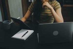 Asian Businesswoman Using laptop computer and working at office with calculator document on desk, doing planning analyzing the financial report, business plan investment, finance analysis concept. photo