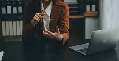 Asian Businesswoman Using laptop computer and working at office with calculator document on desk, doing planning analyzing the financial report, business plan investment, finance analysis concept. photo