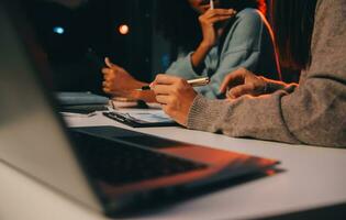 Team of software developers working on big project late at night in neon light trying to finish before deadline photo