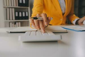 Close up woman work on project sit at desk use laptop and calculator, look at pc screen with diagrams, calculates bills, check financial documents, leads accounting of company, plan investment concept photo
