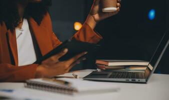 Woman sitting at her desk in home office working late at night using laptop computer female web designer working overtime remotely from home photo