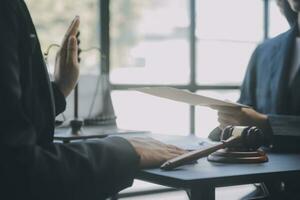 Business and lawyers discussing contract papers with brass scale on desk in office. Law, legal services, advice, justice and law concept picture with film grain effect photo