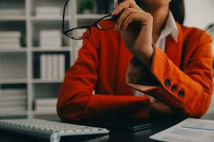 Portrait of Young Asian woman hand freelancer is working her job on computer tablet in modern office. Doing accounting analysis report real estate investment data, Financial and tax systems concept. photo