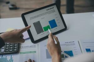 Financial analysts analyze business financial reports on a digital tablet planning investment project during a discussion at a meeting of corporate showing the results of their successful teamwork. photo