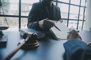 Business and lawyers discussing contract papers with brass scale on desk in office. Law, legal services, advice, justice and law concept picture with film grain effect photo