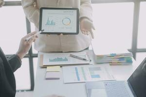 Financial analysts analyze business financial reports on a digital tablet planning investment project during a discussion at a meeting of corporate showing the results of their successful teamwork. photo