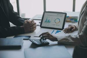 Financial analysts analyze business financial reports on a digital tablet planning investment project during a discussion at a meeting of corporate showing the results of their successful teamwork. photo
