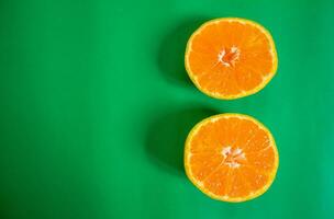 Sliced tangerine isolated on a green background. Top view, copy space. photo