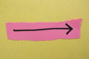 Black arrow sign on a pink paper photo