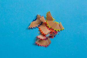 Pencil shavings isolated on a blue background. Top view, flat lay. photo