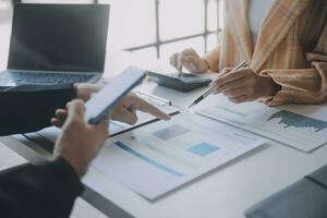 Financial analysts analyze business financial reports on a digital tablet planning investment project during a discussion at a meeting of corporate showing the results of their successful teamwork. photo