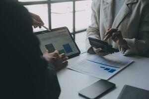 Financial analysts analyze business financial reports on a digital tablet planning investment project during a discussion at a meeting of corporate showing the results of their successful teamwork. photo