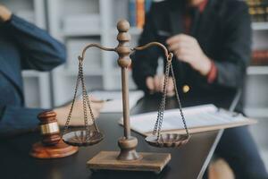 Business and lawyers discussing contract papers with brass scale on desk in office. Law, legal services, advice, justice and law concept picture with film grain effect photo