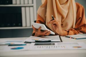 mujer de negocios o contadora que trabaja en inversiones financieras en calculadora, cálculo, análisis de negocios y crecimiento de marketing en gráficos de datos de documentos financieros, contabilidad, concepto económico y comercial. foto