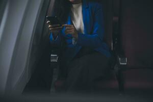 Young Asian business woman talking on smartphone, businesswoman working while flying at plane, Young woman using the internet at airplane, Air travel, long flight. photo