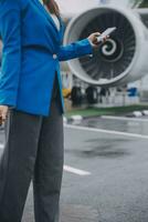 Young asian woman in international airport, using mobile smartphone and checking flight at the flight information board photo