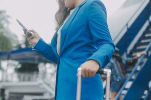 Young asian woman in international airport, using mobile smartphone and checking flight at the flight information board photo