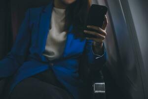 Young Asian business woman talking on smartphone, businesswoman working while flying at plane, Young woman using the internet at airplane, Air travel, long flight. photo