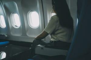 Silhouette of woman looks out the window of an flying airplane. Passenger on the plane resting beside the window. photo