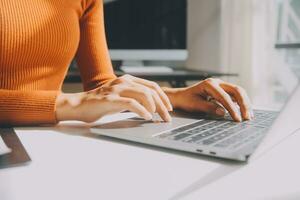Asian Businesswoman Using laptop computer and working at office with calculator document on desk, doing planning analyzing the financial report, business plan investment, finance analysis concept. photo