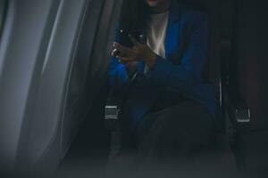 Young Asian business woman talking on smartphone, businesswoman working while flying at plane, Young woman using the internet at airplane, Air travel, long flight. photo