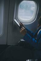 Young Asian business woman talking on smartphone, businesswoman working while flying at plane, Young woman using the internet at airplane, Air travel, long flight. photo