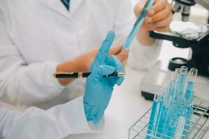 Scientist or medical in lab coat working in biotechnological laboratory, Microscope equipment for research with mixing reagents in glass flask in clinical laboratory. photo