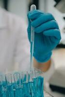 Scientist or medical in lab coat working in biotechnological laboratory, Microscope equipment for research with mixing reagents in glass flask in clinical laboratory. photo
