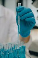 Scientist or medical in lab coat working in biotechnological laboratory, Microscope equipment for research with mixing reagents in glass flask in clinical laboratory. photo