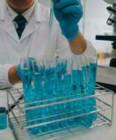 Scientist or medical in lab coat working in biotechnological laboratory, Microscope equipment for research with mixing reagents in glass flask in clinical laboratory. photo