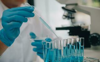 Scientist or medical in lab coat working in biotechnological laboratory, Microscope equipment for research with mixing reagents in glass flask in clinical laboratory. photo