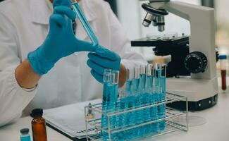 Scientist or medical in lab coat working in biotechnological laboratory, Microscope equipment for research with mixing reagents in glass flask in clinical laboratory. photo