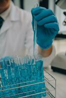 Scientist or medical in lab coat working in biotechnological laboratory, Microscope equipment for research with mixing reagents in glass flask in clinical laboratory. photo