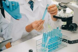 Scientist or medical in lab coat working in biotechnological laboratory, Microscope equipment for research with mixing reagents in glass flask in clinical laboratory. photo