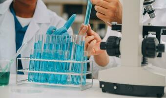 Scientist or medical in lab coat working in biotechnological laboratory, Microscope equipment for research with mixing reagents in glass flask in clinical laboratory. photo