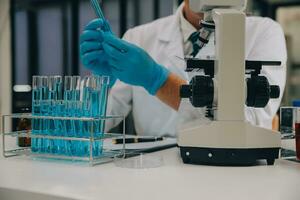 Scientist or medical in lab coat working in biotechnological laboratory, Microscope equipment for research with mixing reagents in glass flask in clinical laboratory. photo