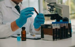 Scientist or medical in lab coat working in biotechnological laboratory, Microscope equipment for research with mixing reagents in glass flask in clinical laboratory. photo